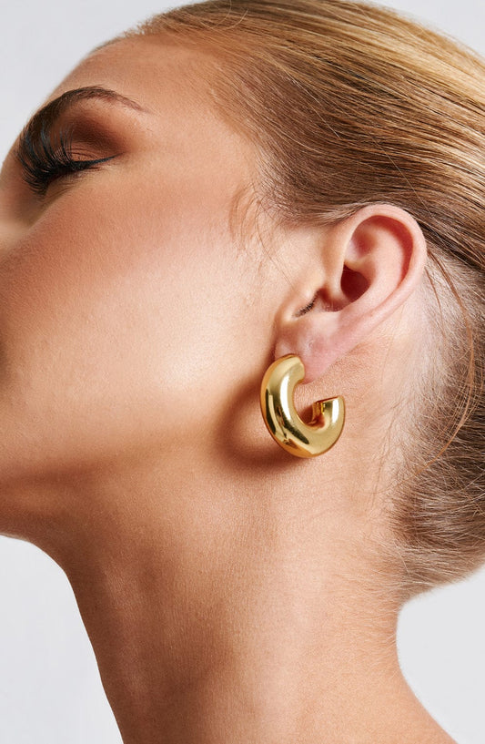 Pendientes Petra de aro dorado curvado, perfil frontal abierto, vista lateral en oreja