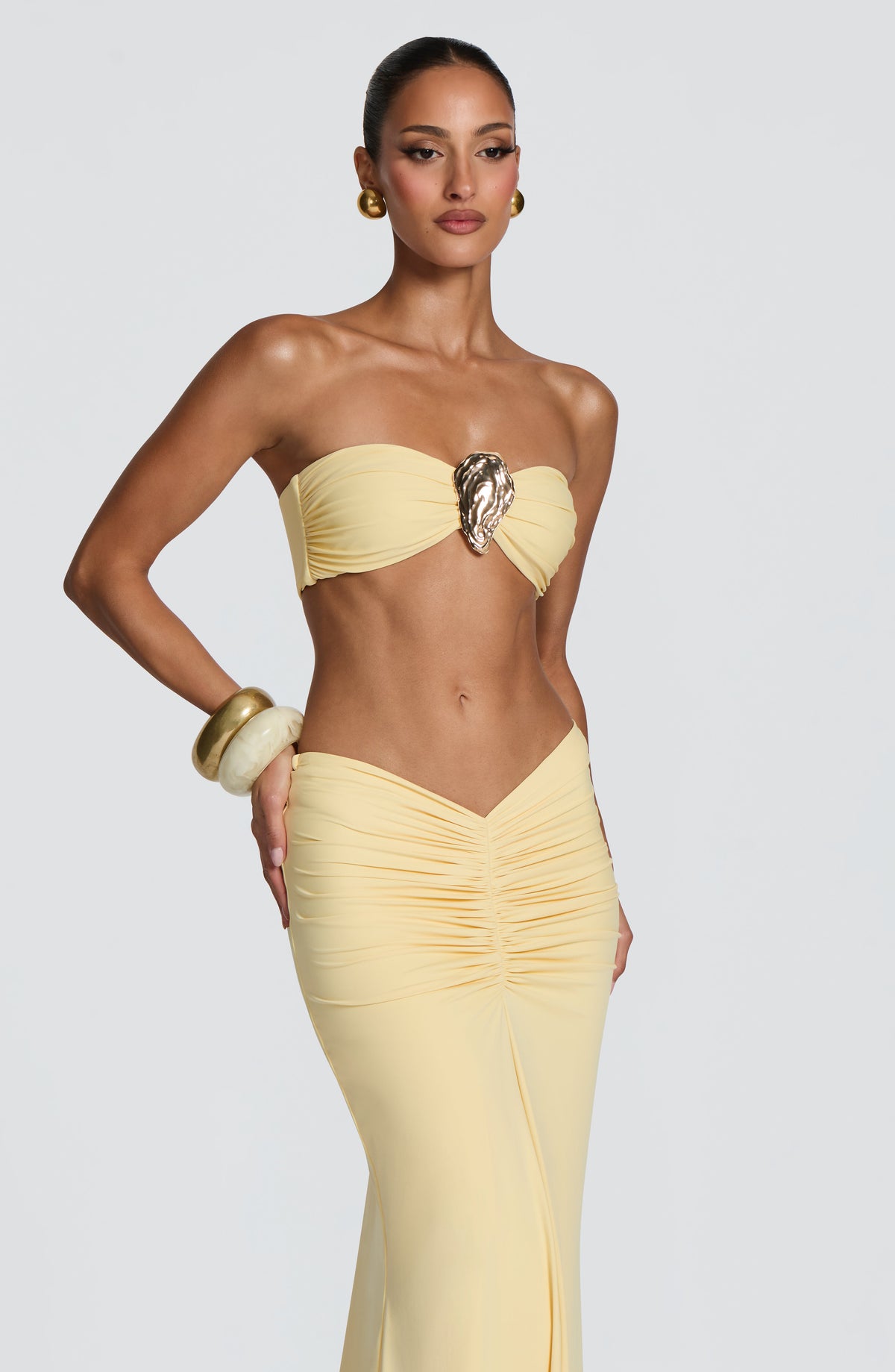 Top de bikini bandeau amarillo limón con adorno ovalado dorado y frunces laterales