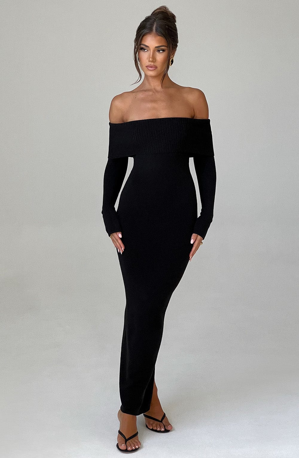 Vestido negro ajustado con escote bardot, manga larga y abertura frontal, vista frontal