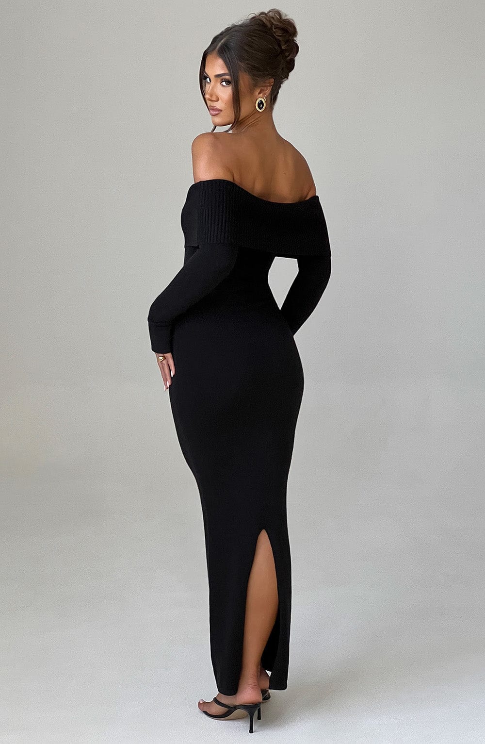 Vestido negro ajustado con escote bardot y abertura en la pierna, vista lateral
