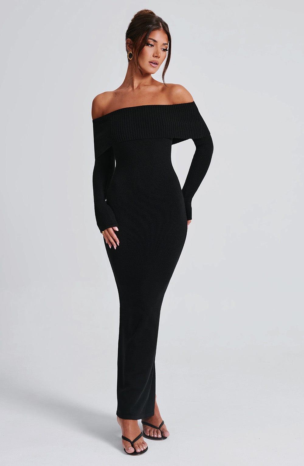 Vestido negro ajustado con hombros descubiertos y abertura frontal, vista tres cuartos