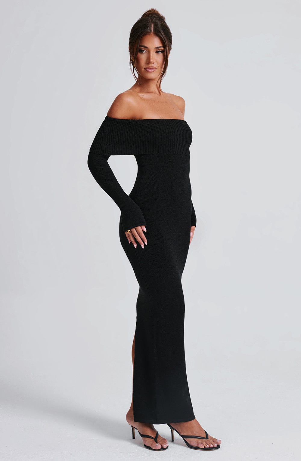 Vestido negro ajustado con escote off-shoulder y abertura en la pierna, vista lateral