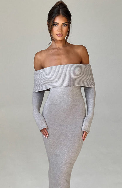 Vestido largo de punto gris claro con hombros descubiertos, manga caída y falda ajustada.