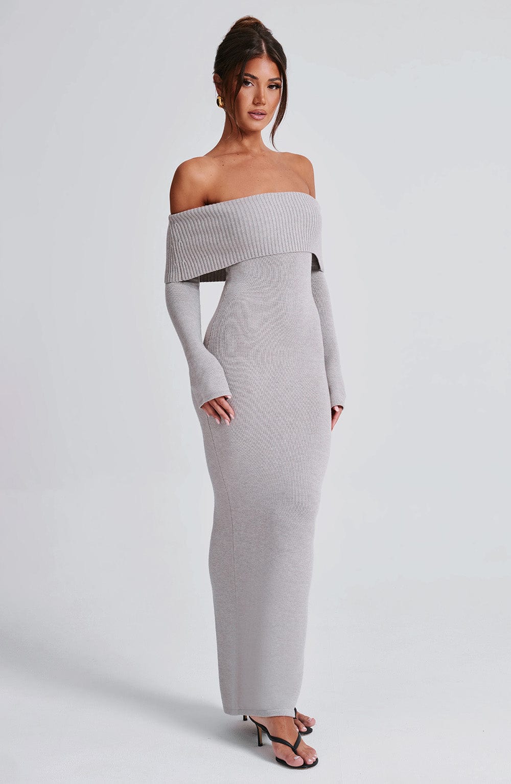 Vestido largo de punto gris claro con escote off-shoulder y falda ajustada hasta el suelo.