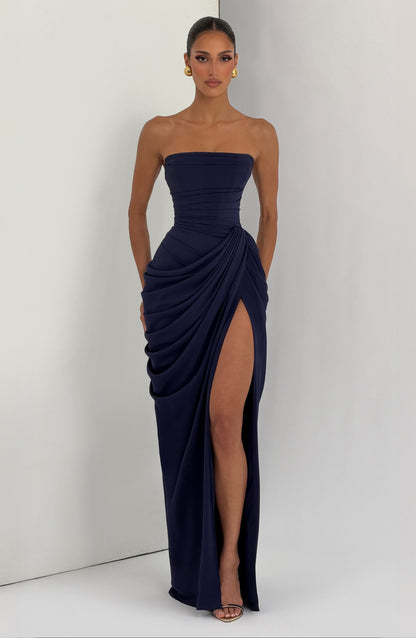 Vestido largo azul oscuro strapless con drapeado envolvente y abertura hasta la rodilla.