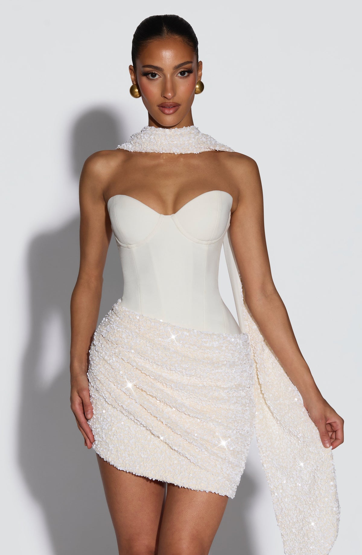 Vestido blanco sin mangas con escote corazón y franja brillante sobre la falda corta.