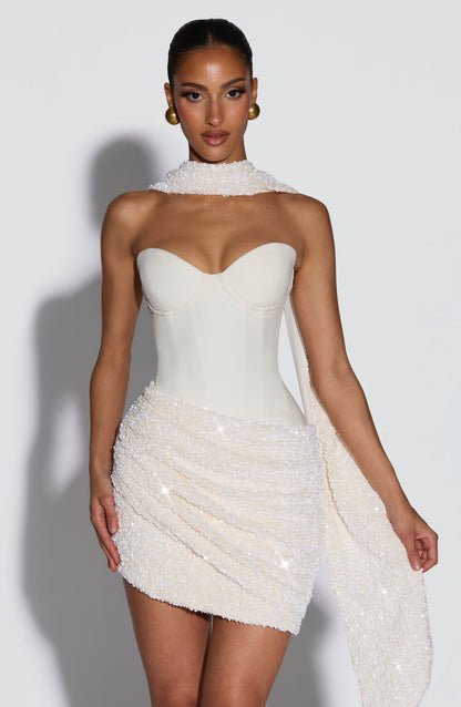 Vestido blanco sin mangas con escote corazón y franja brillante sobre la falda corta.