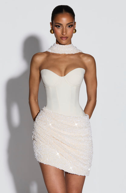 Vestido blanco sin mangas con escote corazón alto y falda corta de pedrería.
