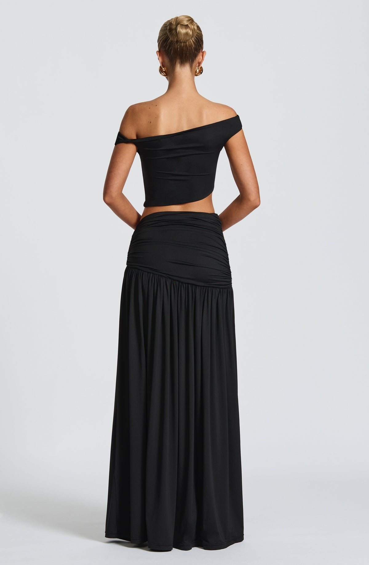 Conjunto negro visto por la espalda: top con escote recto y falda larga fruncida.