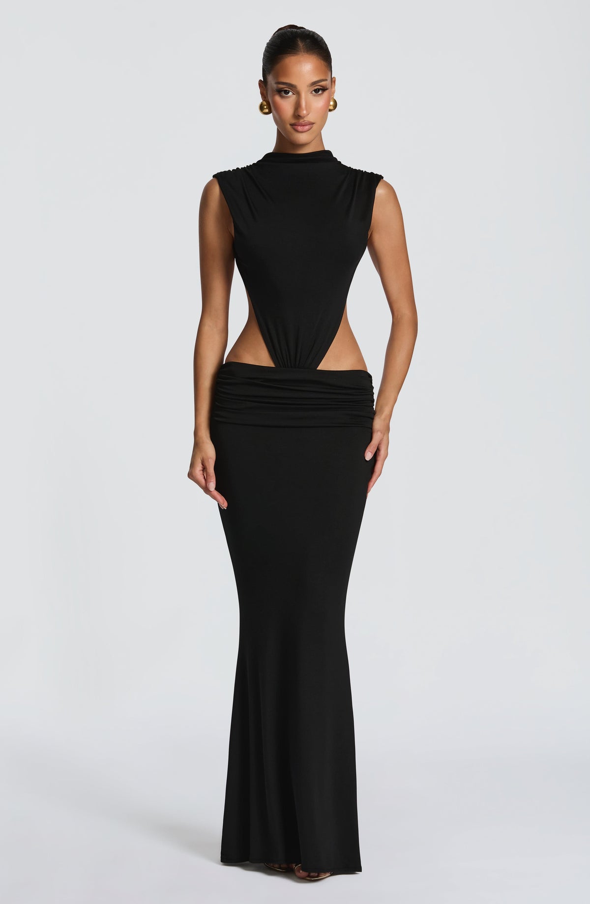 Vestido negro sin mangas, escote alto y abertura frontal en la cintura; falda larga