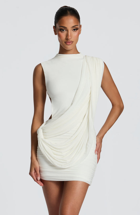 Vestido blanco sin mangas con cuello alto y drapeado lateral cruzado.