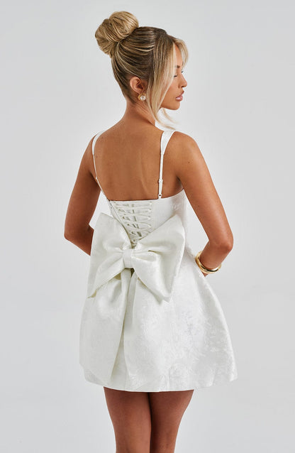 Vestido blanco con espalda descubierta y lazo grande en la zona media, tirantes finos