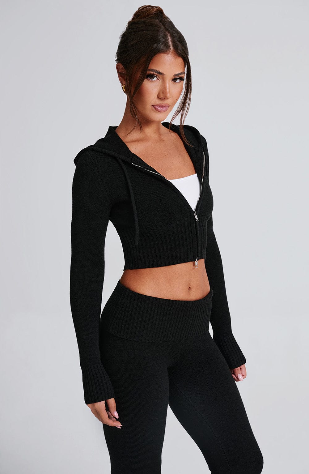 Sudadera negra corta con capucha, cremallera frontal y tejido acanalado en mangas y cintura.