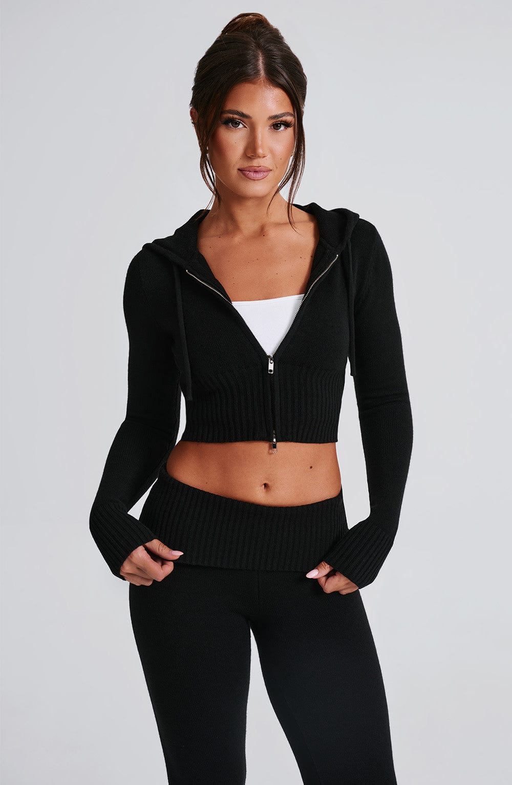 Sudadera negra con capucha y cremallera frontal, tejido de punto fino y bajo acanalado.