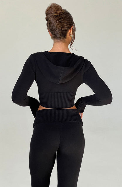 Sudadera negra con capucha, vista trasera con tejido acanalado y cintura entallada.