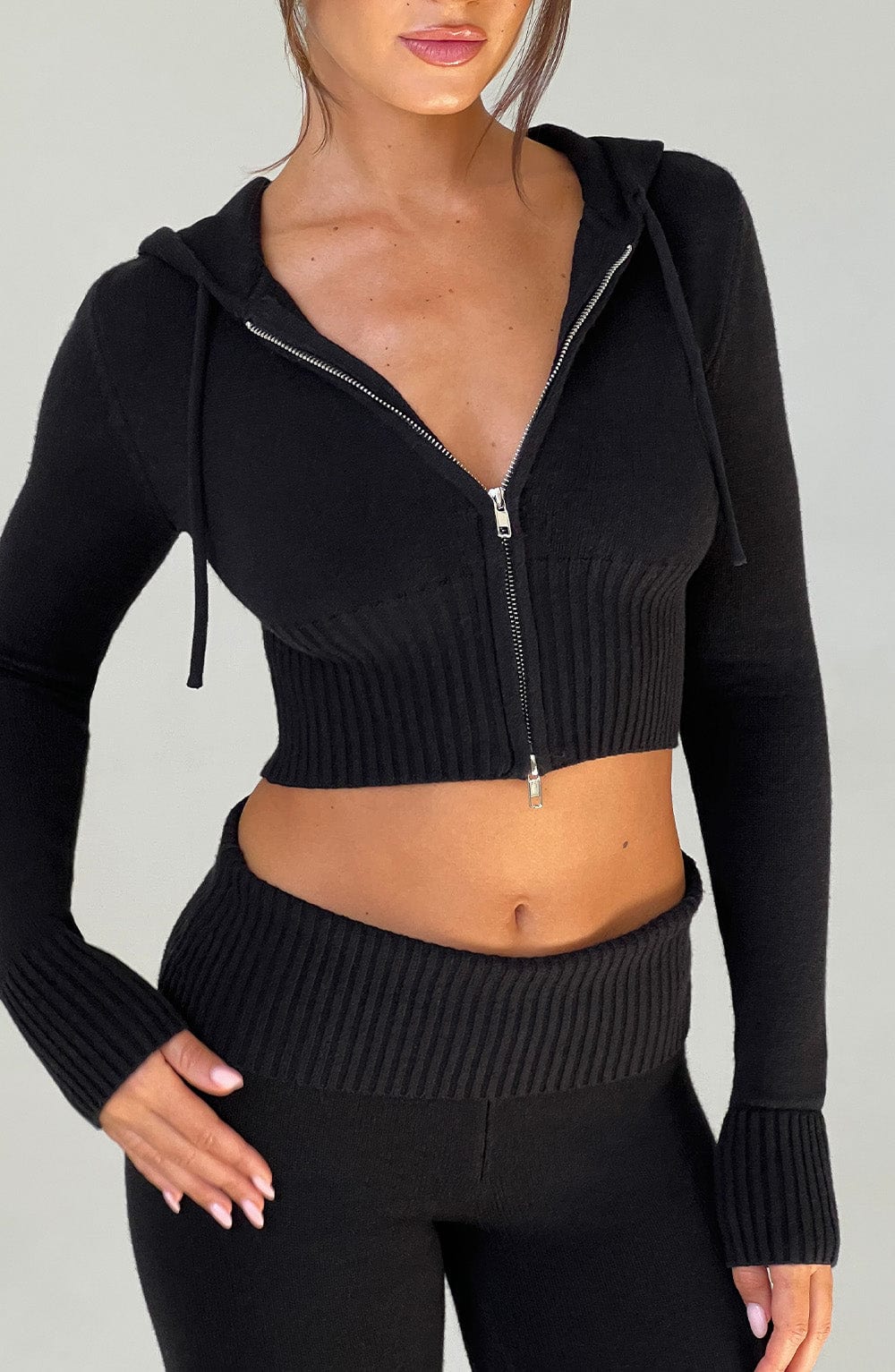 Sudadera negra corta de punto con cremallera y capucha, detalle frontal