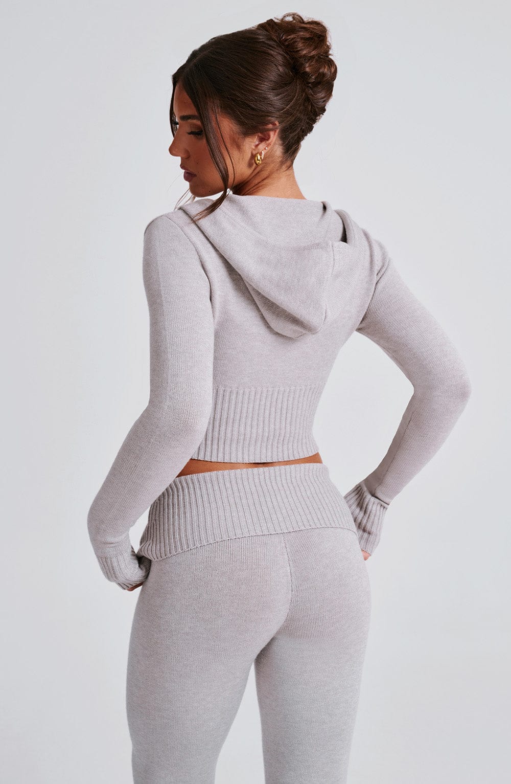 Conjunto gris claro: sudadera con capucha y espalda visible, pantalón a juego.