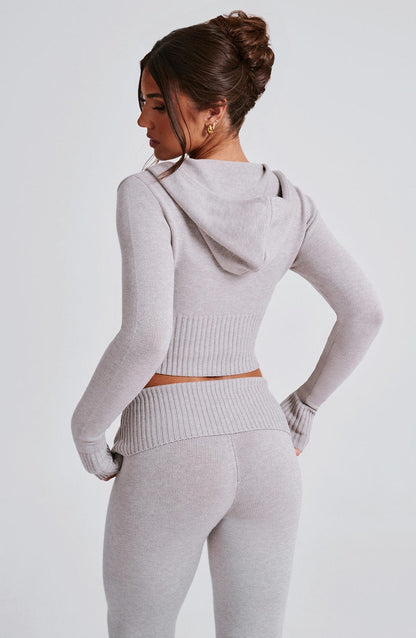 Conjunto gris claro: sudadera con capucha y espalda visible, pantalón a juego.