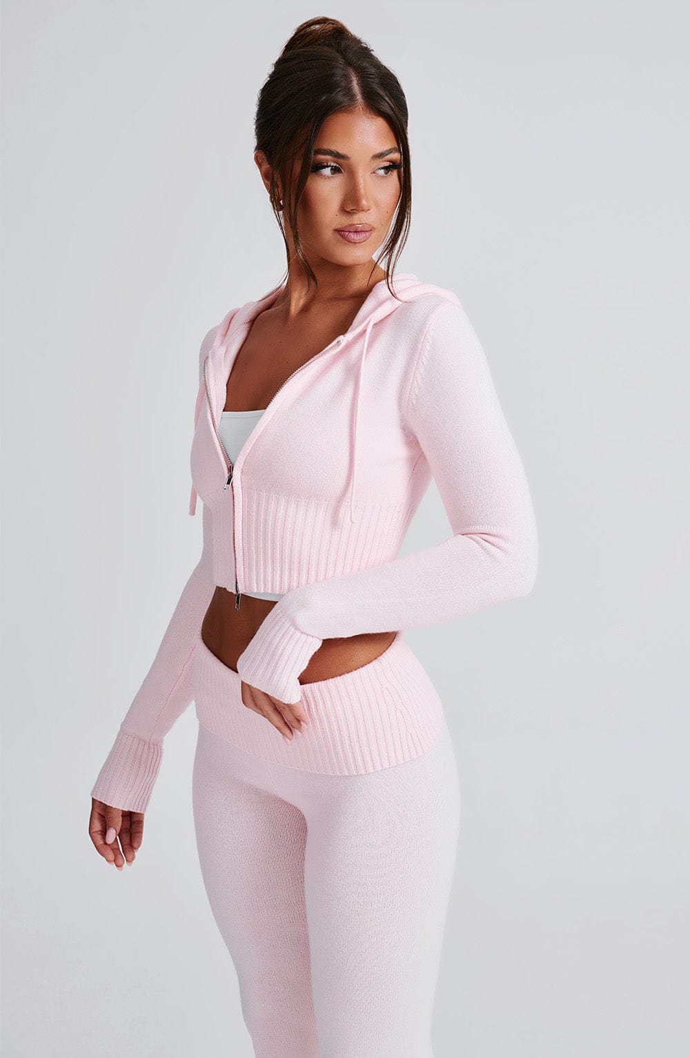 Sudadera rosa con capucha y cremallera; tejido acanalado y cordones visibles, vista lateral