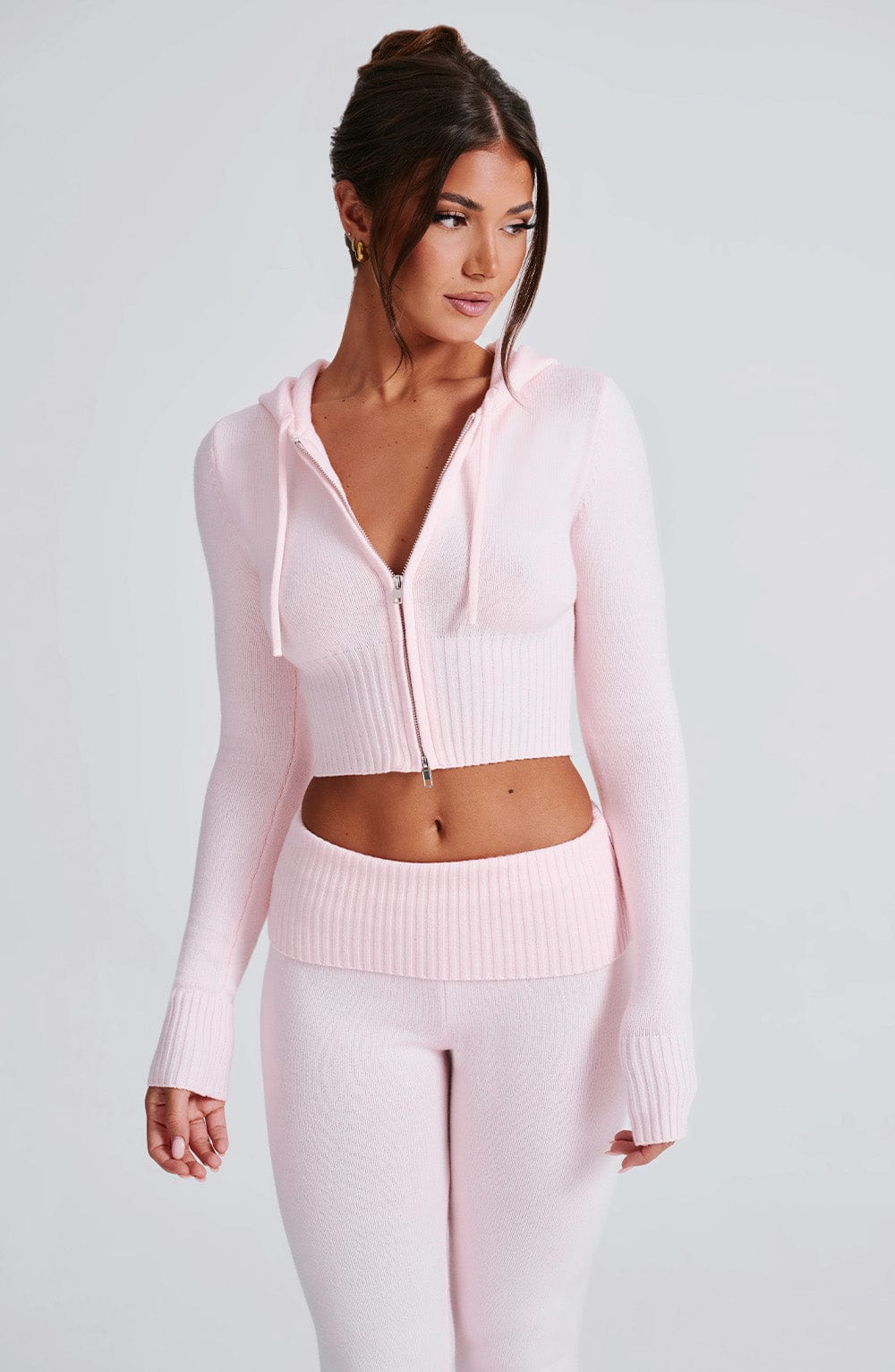 Sudadera rosa con capucha y cremallera; detalle del bajo y pantalón de punto