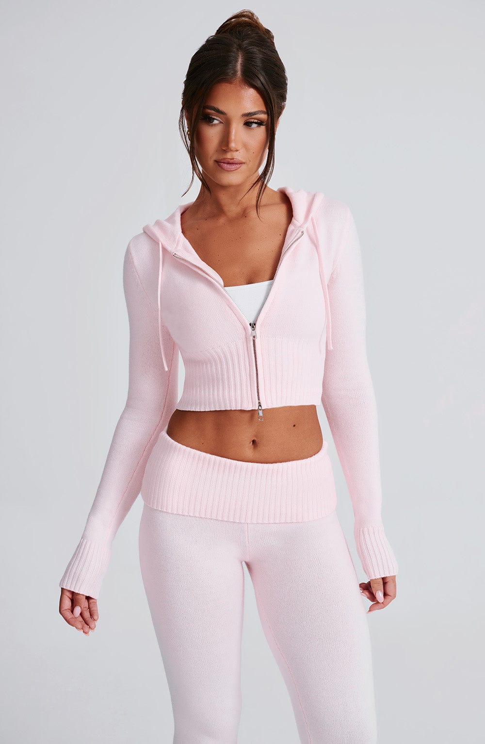 Sudadera rosa con capucha y cremallera, bajo corte corto; pantalón de punto