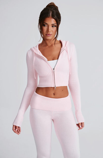 Sudadera rosa con capucha y cremallera, bajo corte corto; pantalón de punto