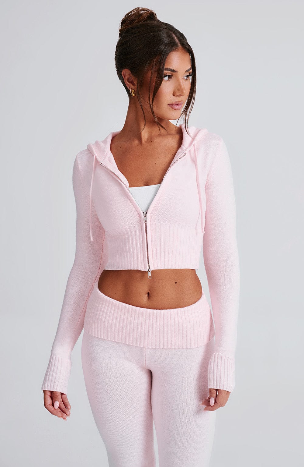 Sudadera rosa con capucha y cierre; pantalón de punto ajustado con bota acampanada