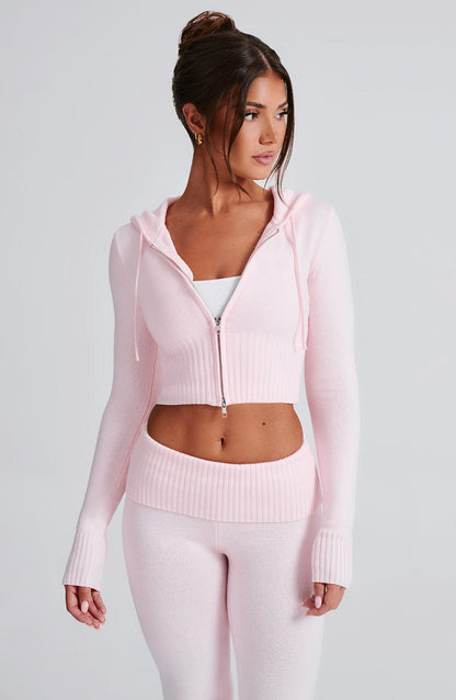 Sudadera rosa con capucha y cierre; pantalón de punto ajustado con bota acampanada