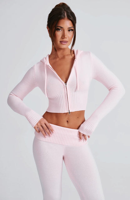 Sudadera rosa con capucha y cremallera, corte corto, sobre pantalón de punto a juego