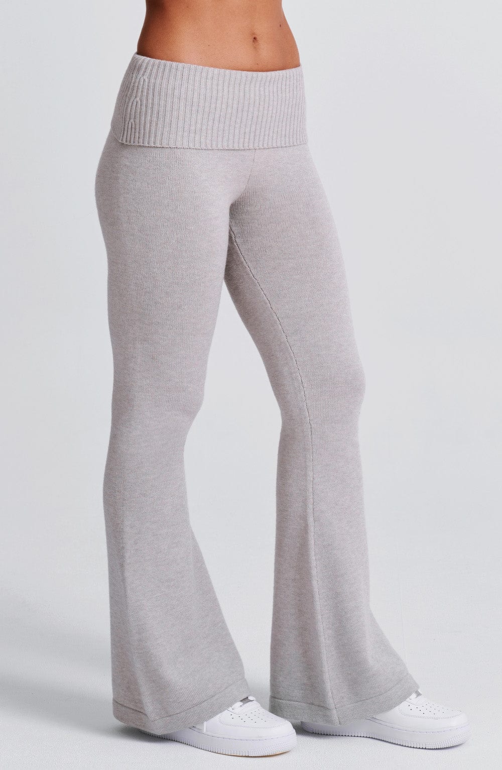 Pantalón de punto gris claro con pierna acampanada y costura a lo largo del muslo.