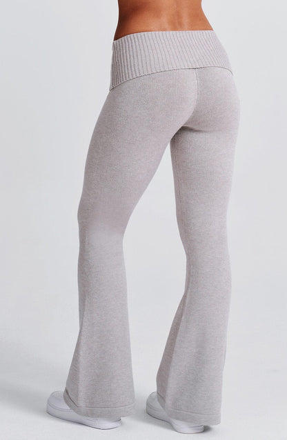 Pantalón acampanado de punto gris claro, costuras visibles y cintura elástica ancha.