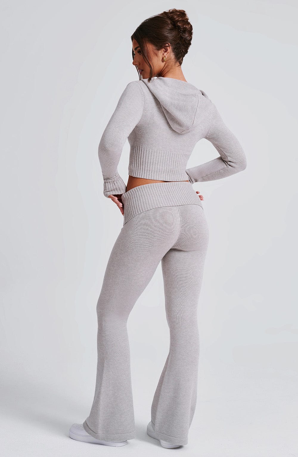 Pantalón acampanado gris claro de punto, espalda y tiro medio con cintura elástica.