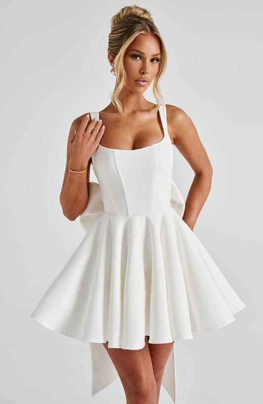 Vestido blanco tipo globo con tirantes finos y escote cuadrado, falda evasé con pliegues.
