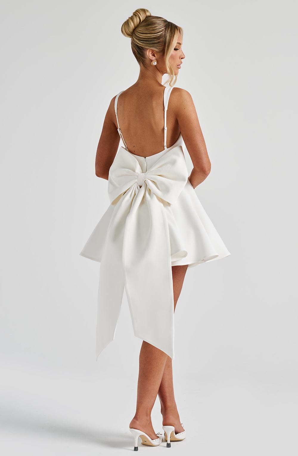 Vestido blanco de espalda descubierta con lazo central y falda con vuelo y cintas largas.