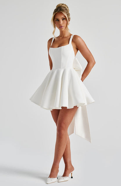 Vestido blanco con tirantes finos, escote cuadrado y falda evasé con vuelo plisado.