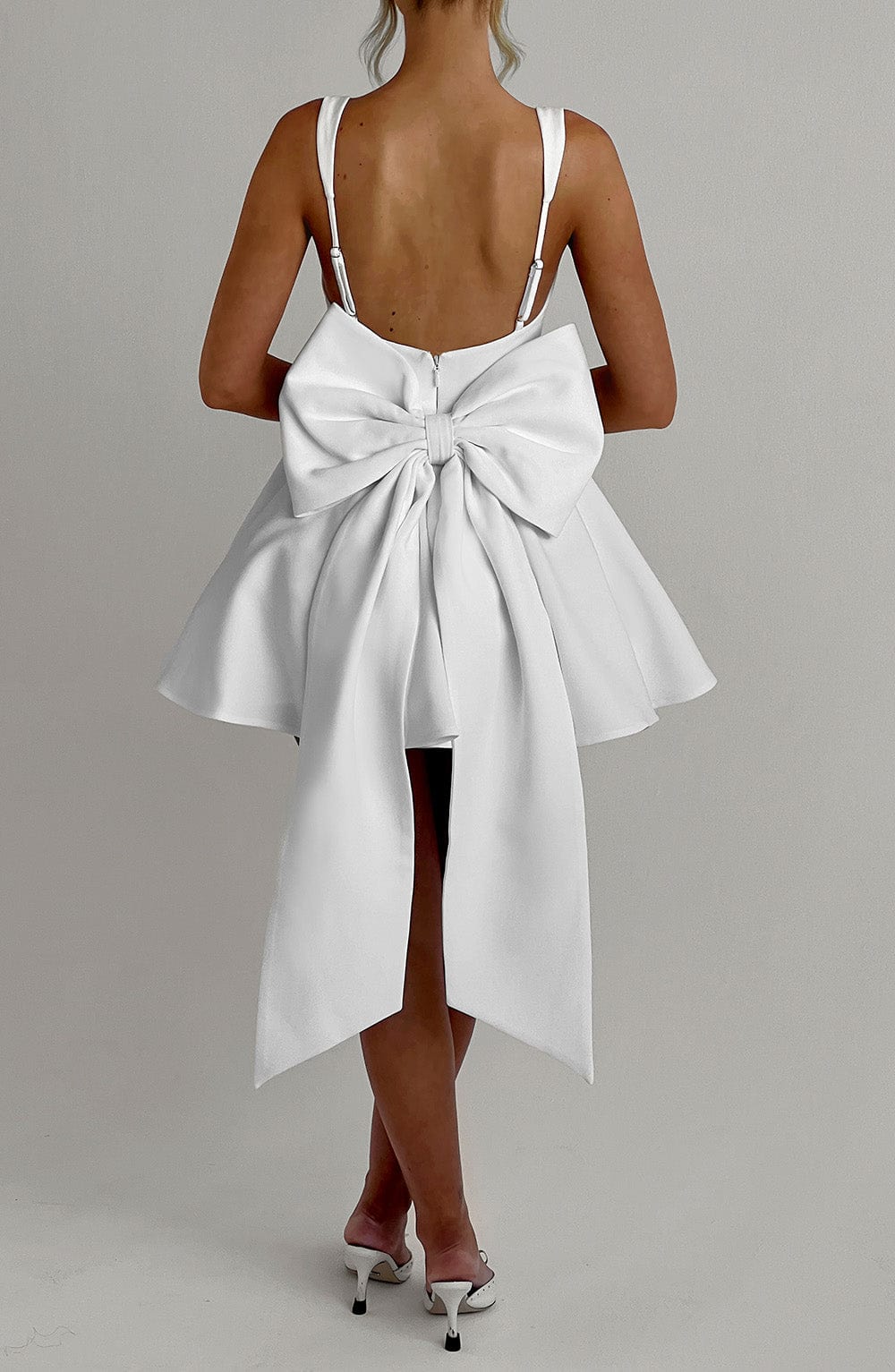Vestido blanco con lazo grande en la espalda y falda abierta con cintas largas.