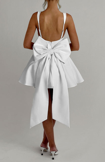 Vestido blanco con lazo grande en la espalda y falda abierta con cintas largas.