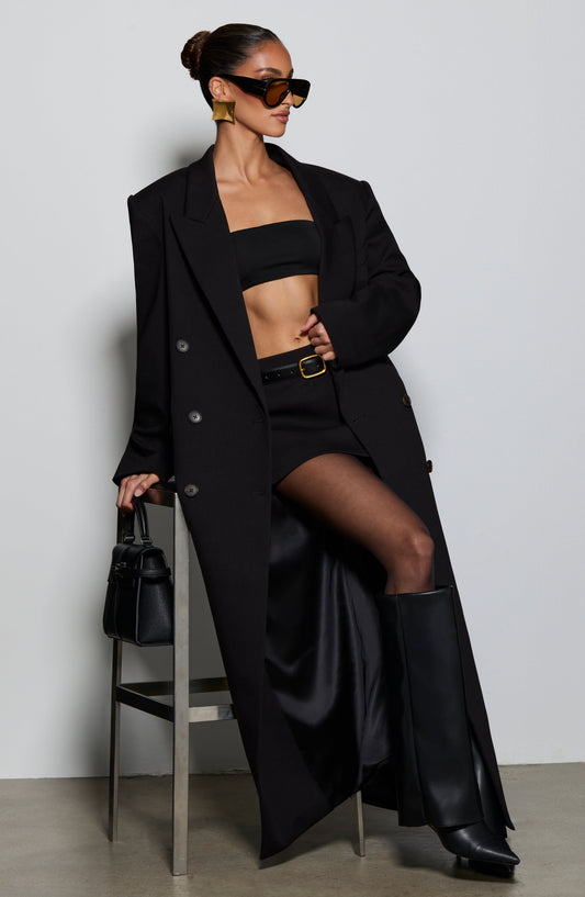 Top negro tipo bandeau sin tirantes, visible bajo el blazer abierto.