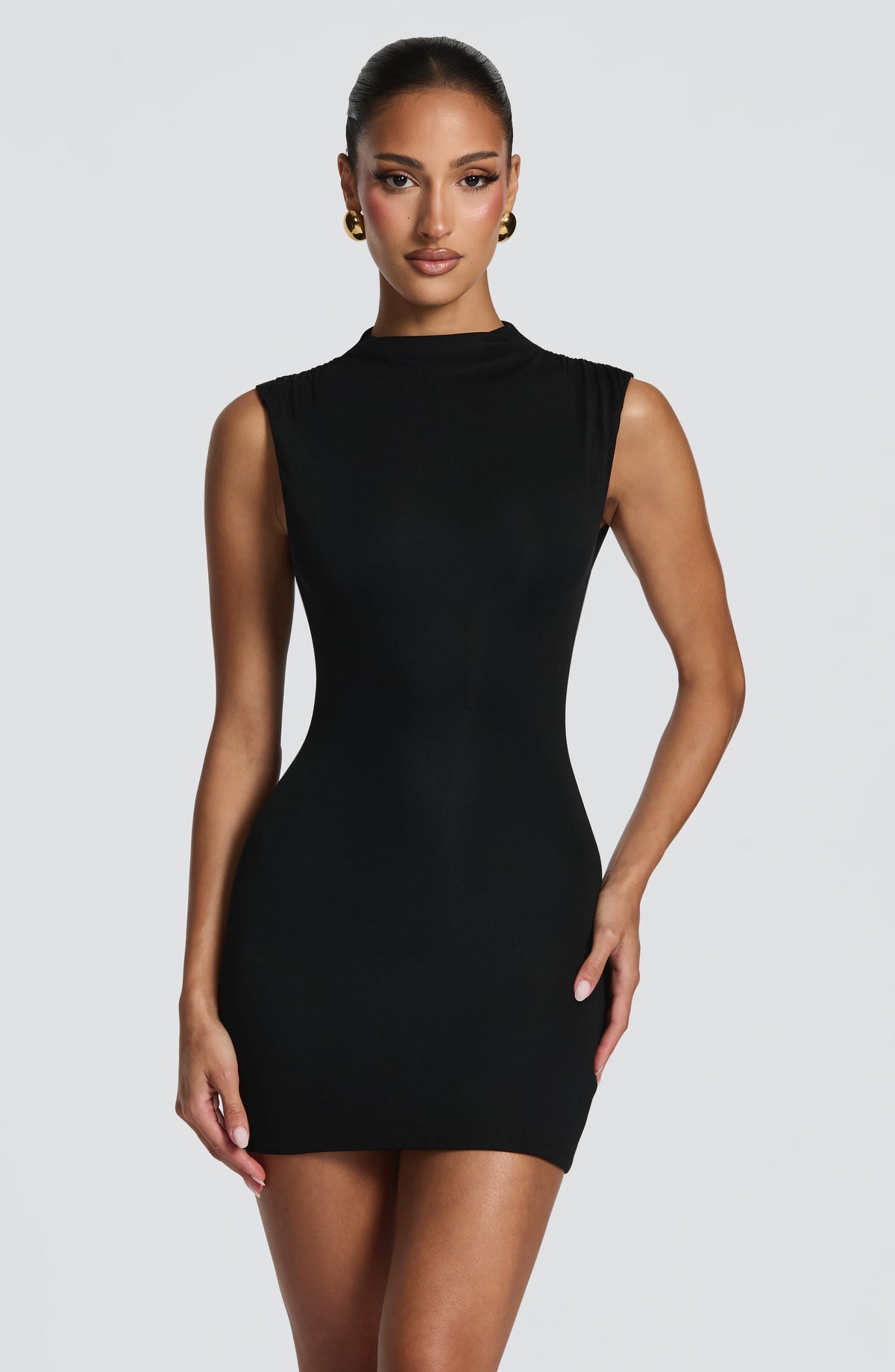Vestido negro entallado sin mangas, cuello alto y línea curva en la cintura