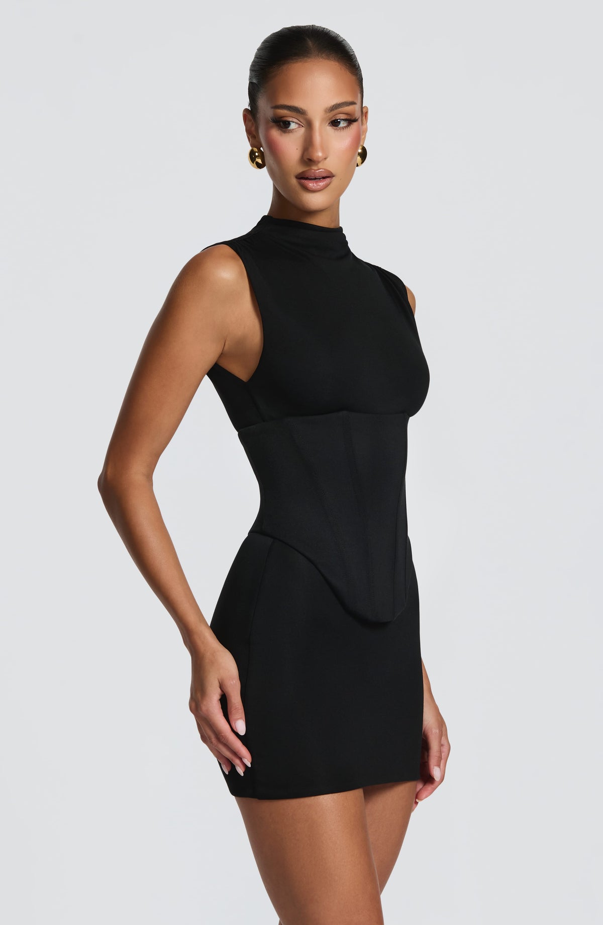 Vestido negro sin mangas con cuello alto y frunce en la cintura, vista lateral