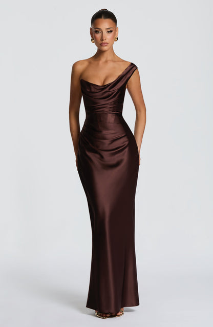 Vestido largo satinado marrón oscuro con drapeado, escote asimétrico y corte entallado.
