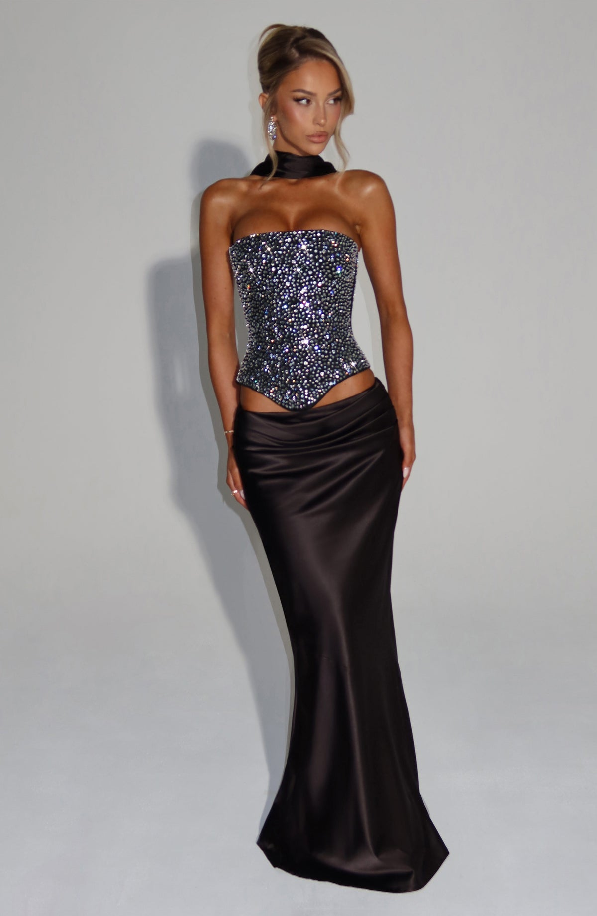 Corsé negro strapless con pedrería y falda satén larga negra, vista de cuerpo completo.