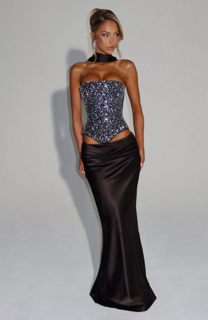 Corsé negro strapless con pedrería y falda satén larga negra, vista de cuerpo completo.